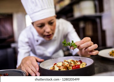 Caucasian female chef garnishing delicious desserts in a plate at hotel