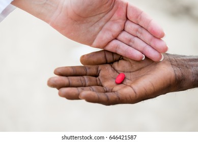 Caucasian Female Doctor Giving Red Pill To African Black Man.Close Up Hands, Unrecognizable People