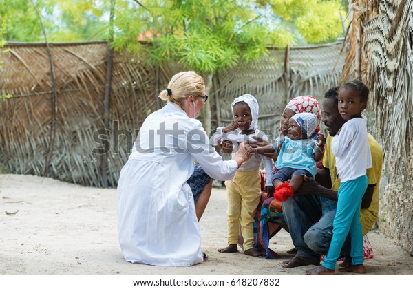 アフリカの小さな女の子の心臓の鼓動と呼吸を聞く白人の女性医師 家族診察 の写真素材 今すぐ編集