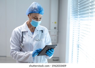 Caucasian female doctor wearing mask and latex gloves using tablet. medicine, health and healthcare services during coronavirus covid 19 pandemic. - Powered by Shutterstock