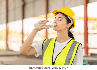 Caucasian female engineer drinking water at the precast factory site, Young forman worker drinking water at construction site - Powered by Shutterstock