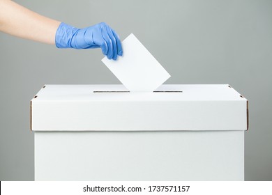 Caucasian Female Hand Wearing Blue Protective Latex Rubber Glove Placing Ballot Paper In Vote Box,side View,prevention Of Spread & Transfer Of Coronavirus At The USA Voting Place, COVID-19 Pandemic US