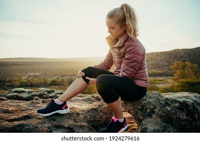 Caucasian Female Hiking On Mountain Injured Leg Holding Knee Sitting On Rock Waiting For Help