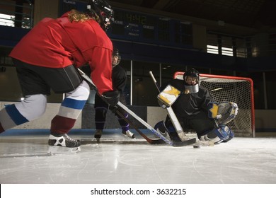 Caucasian Female Hockey Player Trying To Make Goal As Goalie Protects The Net.