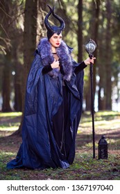 Caucasian Female Poses in Maleficent Clothing and Horns in Spring Forest. Holding Crook with Mirror Ball.Vertical Image