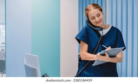 Caucasian female practitioner working at reception desk while answering phone calls and scheduling appointments in medical clinic. Hospital concept. - Powered by Shutterstock