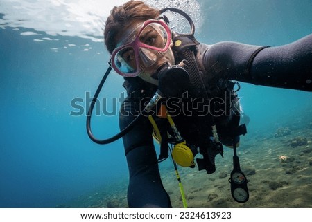 Caucasian Female scuba diver taking a selfie underwater