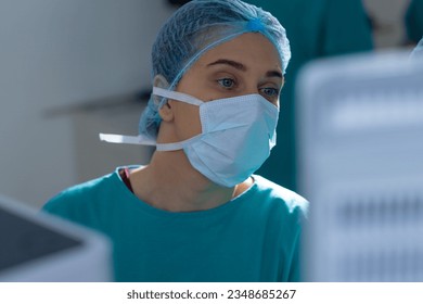 Caucasian female surgeon wearing surgical gown and face mask in operating theatre at hospital. Hospital, surgery, hygiene, medicine, healthcare and work, unaltered. - Powered by Shutterstock