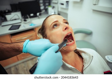 Caucasian Female Teen Busy In Dentist Room Cleaning Teeth By Oral Hygienist 