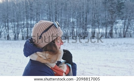 Caucasian Female Traveller Tourist Warming Up Drinking Hot Drink from Vacuum Flask Thermos during Cold Winter Morning Mountain Forest Hike Closeup