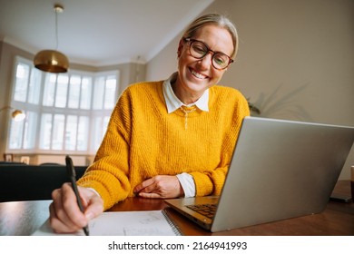 caucasian female working from home writing on documents 