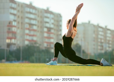 Caucasian Fit Woman Does Stretching In Deep Lunge On A On The Sports Area Outdoor In Summer, Selective Focus, Back Bending And Hip Joint Mobility, Selective Focus