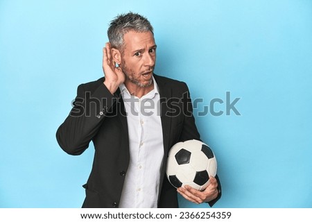 Caucasian football coach, middle-aged on blue set trying to listening a gossip.