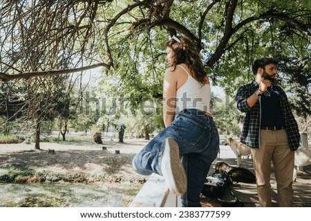 Caucasian friends enjoy an autumn day in a city park. Casual and carefree, they relax under a tree, talking and having fun.