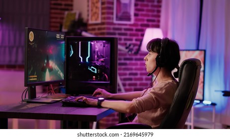 Une jeune fille caucasienne se reposant en jouant à une simulation de tir d'espace à rythme rapide sur un ordinateur professionnel en parlant avec un casque de jeu. Femme jouant en continu sur Internet rpg jeu d'action de tournoi.
