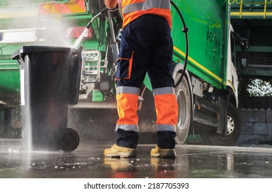 Caucasian Garbage Truck Operator Pressure Washing Black Trash Can After Waste Collection. Junk Truck Built In Washer Using.