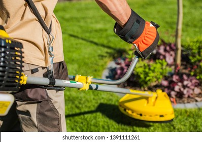 Caucasian Gardener with Gasoline Brush Cutter and String Trimmer on His Shoulder. Trimming Garden Grass. Landscape Maintenance.