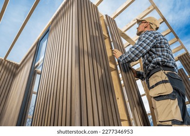 Caucasian General Construction Worker in His 40s Building Small Modern Garden Shed Using Wood and Composite Materials.