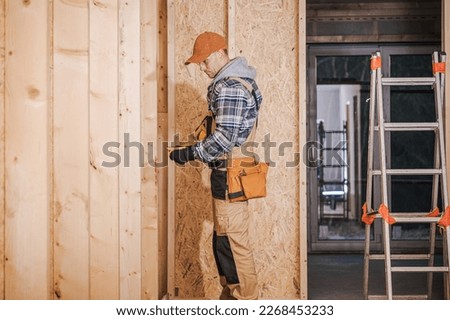 Caucasian General Contractor at Wooden Residential House Construction Site. Industrial Theme.