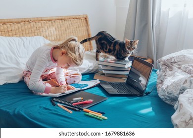 Caucasian Girl Child Sitting In Bed And Learning Online On Laptop Internet. Virtual Class Lesson On Video During Self Isolation At Home. Distant Remote Video Education. Modern School Study For Kids.