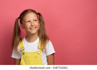 Caucasian Girl Child In Yellow Clothes Waist-length Portrait Looking Away On A Pink Background