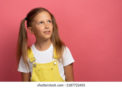 Caucasian Girl Child In Yellow Clothes Waist-length Portrait Looking Away On A Pink Background