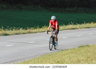 Caucasian Girl Cyclist With Professional Racing Sports Gear Riding On An Open Road Cycling Route