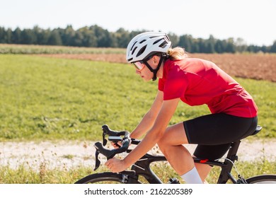 Caucasian Girl Cyclist With Professional Racing Sports Gear Riding On An Open Road Cycling Route