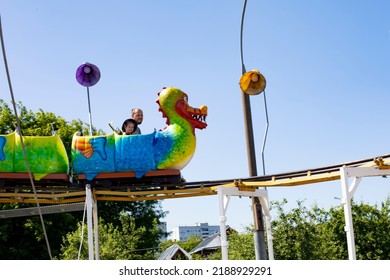 Caucasian Girl With Dad Riding A Carousel, Family Vacation Rollercoaster, Child 4 Years Old On A Dragon Horizontal Photography