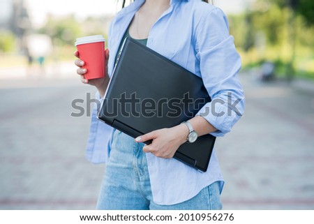 Caucasian girl holding laptop and a cup of coffee