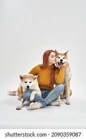 Caucasian girl hugging and caressing Shiba Inu dogs in white studio. Concept of relationship between human and animal. Idea of owner and pet friendship. Enjoy young woman with closed eyes. Copy space