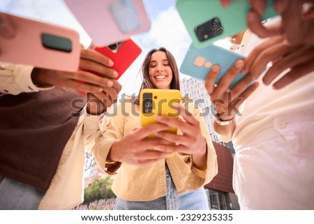 Caucasian girl looking at happy cell phone. Low angle view of group friends addicted to technology. People gathered in circle using mobile. New generations and communication through social networks.