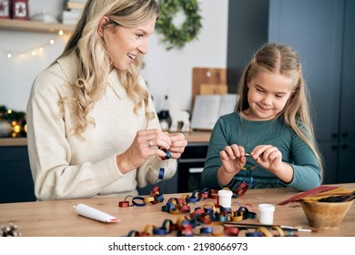 Caucasian Girl And Mother Preparing DIY Paper Chain For Christmas Tree And Talking