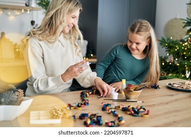 Caucasian Girl And Mother Preparing DIY Paper Chain For Christmas Tree And Talking