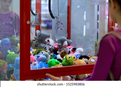 Caucasian girl playing toy crane vending machine, Claw Game or Cabinet to Catch the Toys. Shopping, holiday activity, game of chance, vacation concept. Selective focus on crane. - Shutterstock ID 1525983806
