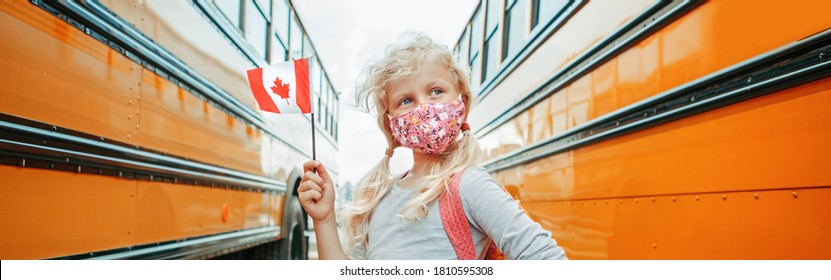 Caucasian Girl Student With Face Mask Holding Canadian Flag. Student Kid Near Yellow School Bus In Canada. Education And Back To School. New Normal During Coronavirus. Web Banner Header.