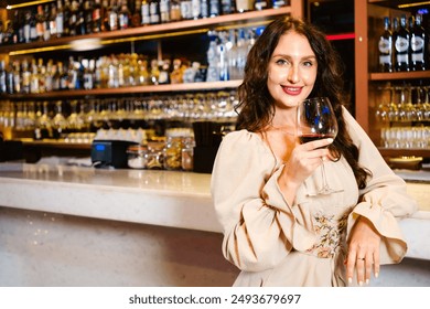 Caucasian glamour woman, wearing a white glitter dress smiling and drinking a glass of wine at a luxury nightclub counter bar with liquor in the background. Attractive woman enjoy and fun hangout - Powered by Shutterstock