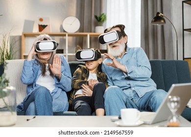 Caucasian grandmother grandson and grandfather wearing vr headset sitting on couch at home. Virtual reality and futuristic technology, retirement and free time concept. - Powered by Shutterstock