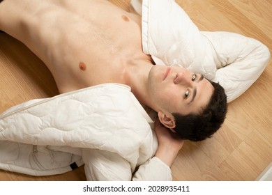 
caucasian guy lying on the floor looking at the camera with shirtless jacket 