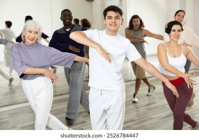 Caucasian guy practising dance moves with other people in dance studio - Powered by Shutterstock