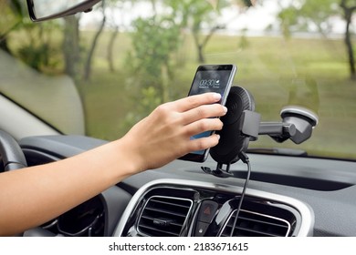 Caucasian hand putting a cellphone on a car phone holder