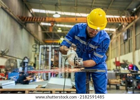 Caucasian handsome male industrial worker work in manufacturing plant. Attractive young man industry factory engineer wear helmet and processes orders and product at manufacturing plant with happiness