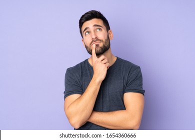 Caucasian handsome man having doubts while looking up over isolated purple background - Shutterstock ID 1654360666