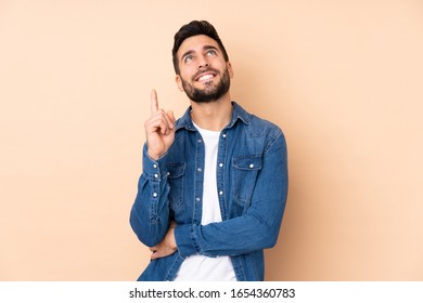 Caucasian handsome man isolated on beige background pointing up a great idea - Shutterstock ID 1654360783