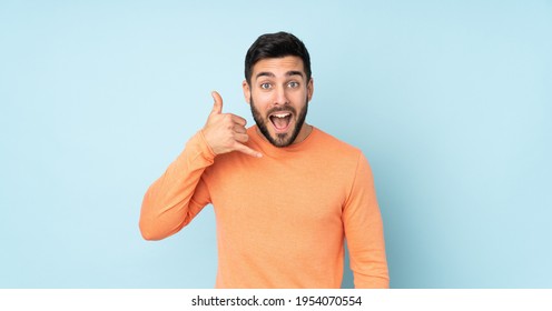 Caucasian Handsome Man Making Phone Gesture. Call Me Back Sign Over Isolated Blue Background