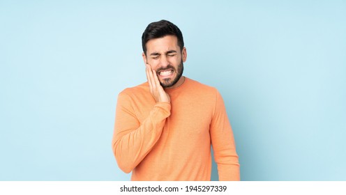 Caucasian handsome man with toothache over isolated blue background