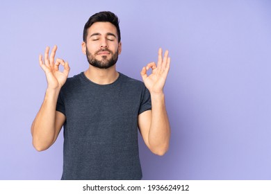 Caucasian Handsome Man In Zen Pose Over Isolated Purple Background