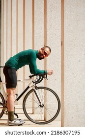 Caucasian Handsome Young Man In Protective Helmet Goes Out For Bicycle Ride Through City Streets On Blurred Background. Cyclist Male Ride Bike Outdoors In Urban.