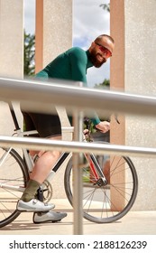 Caucasian Handsome Young Man In Protective Helmet Goes Out For Bicycle Ride Through City Streets On Blurred Background. Cyclist Male Ride Bike Outdoors In Urban.