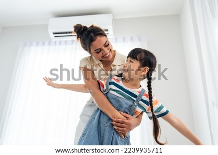 Caucasian happy family, parent spend free time with kid together at home. Adorable young girl daughter hug mother while playing with happiness in living room. Activity relationship in house concept.